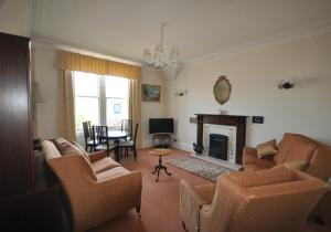 a living room with a couch and chairs and a fireplace at Sandstones in North Berwick
