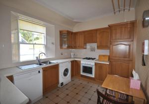 北貝里克的住宿－Sandstones，厨房配有木制橱柜、水槽和洗碗机。