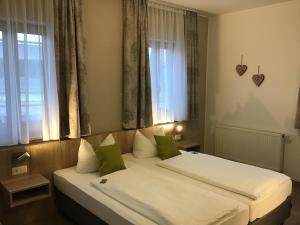 Schlafzimmer mit einem Bett mit weißer Bettwäsche und grünen Kissen in der Unterkunft Gasthof Hotel Esterer in Rosenheim