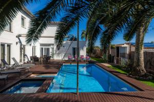 una piscina en el patio trasero de una casa con palmeras en Villa Amarador, en Santanyí