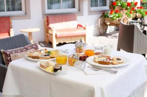 a table topped with plates of food and orange juice at Hotel Valacia in Pozza di Fassa