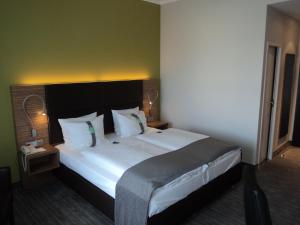 ein Schlafzimmer mit einem großen Bett in einem Hotelzimmer in der Unterkunft Holiday Inn Leipzig Günthersdorf, an IHG Hotel in Kötschlitz