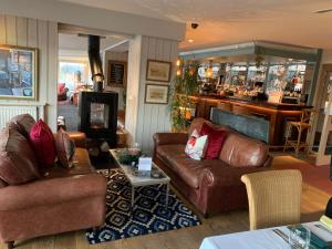 a living room with two leather couches and a bar at Hotel Wroxham in Wroxham