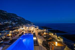 una piscina con vistas al océano por la noche en Hotel Villa Franca, en Positano