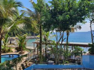 a resort with a pool and palm trees and the ocean at Pousada Morada das Ilhas in Boicucanga