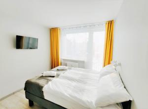 a bedroom with a white bed with an orange curtain at Zefiro Ogrody in Gdańsk