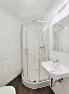 a white bathroom with a shower and a sink at Zefiro Ogrody in Gdańsk