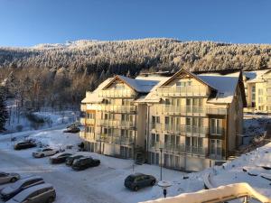 a large apartment building in the snow with parked cars at Apartment Czarna Góra Resort ISCHGL 30, Sienna in Sienna
