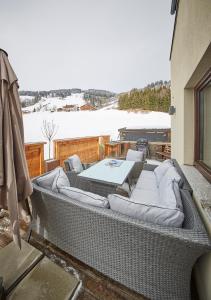 a large wicker couch on a balcony with snow at SonnAlm Appartements in Saalbach Hinterglemm