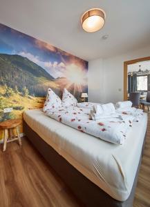 a bedroom with a large bed with a painting on the wall at SonnAlm Appartements in Saalbach Hinterglemm