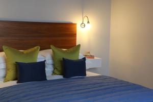 a bedroom with a bed with blue and green pillows at Belgravia Apartments in London
