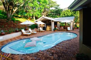 a swimming pool with chairs and tables and umbrellas at Madi a Thavha Mountain Lodge in Louis Trichardt