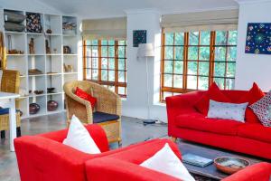 a living room with red couches and chairs at Madi a Thavha Mountain Lodge in Louis Trichardt