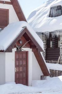 una casa con una puerta roja en la nieve en Holiday Cottage Pedja, en Kopaonik