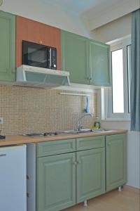 a kitchen with green cabinets and a microwave at Bristol Sea View Apartments in Kos Town
