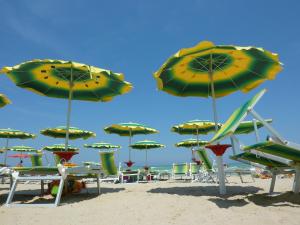eine Gruppe von Stühlen und Sonnenschirmen an einem Strand in der Unterkunft Green Marine L2 Silvi Vacanza in Silvi Marina