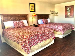 Best Inn Texas في Levelland: غرفة فندقية بسريرين وبطانيات حمراء