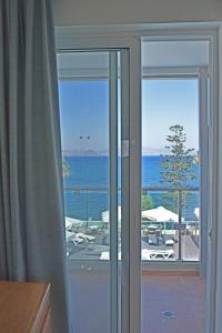a sliding glass door with a view of the ocean at Bristol Sea View Apartments in Kos Town