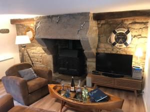 sala de estar con chimenea de piedra y TV en Pierre et mer au cœur de Saint Cado, en Belz