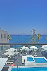 a swimming pool with chairs and umbrellas and the ocean at Bristol Sea View Apartments in Kos