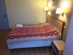 Bett in einem Hotelzimmer mit Tagesdecke in der Unterkunft Hôtel de la Gare in Romans-sur-Isère