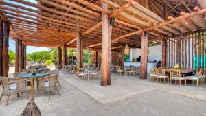 a patio area with chairs, tables, and tables with umbrellas at Aura Hotel Barú in Barú