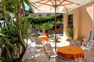 eine Terrasse mit einem orangenen Tisch, Stühlen und einem Sonnenschirm in der Unterkunft Hotel Saturno in Chianciano Terme