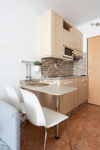 a kitchen with white chairs and a table and cabinets at Apartamentos Ohana - Edificio Tonillo in Los Cristianos