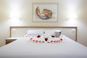 a white bed with a bowl and flowers on it at Hotel Dan Inn Sorocaba in Sorocaba