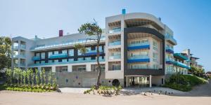a building on the beach with a palm tree in front of it at Triplex con terraza única a 50 mts del mar in Carilo