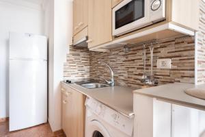 a small kitchen with a sink and a microwave at Apartamentos Ohana - Edificio Tonillo in Los Cristianos