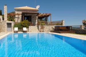 a swimming pool with two chairs and a house at Lefkada Villas by Omikron Selections in Vavkerí