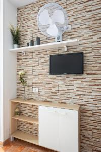 a living room with a tv on a brick wall at Apartamentos Ohana - Edificio Tonillo in Los Cristianos