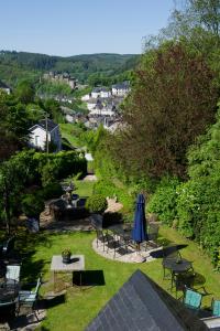 a garden with tables and chairs and an umbrella at Hotel La Ferronniere in Bouillon