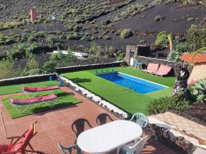 een achtertuin met een zwembad en een tafel en stoelen bij FINCA LA JORADITA in Tamaduste