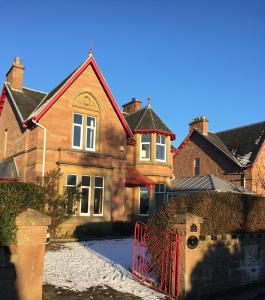 una casa con una puerta roja delante de ella en Ronas House, en Inverness