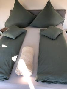 a bed with green pillows and a towel on it at Wohnen beim Brotsommelier - Alpenkruste in Darmstadt