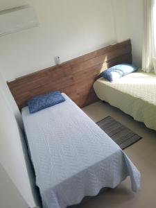 een slaapkamer met 2 bedden en een hoofdeinde bij Apto Queen D'Arte Bombinhas in Bombinhas
