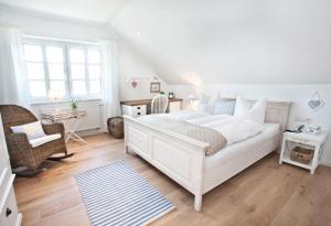 a white bedroom with a large white bed and a chair at Belle Maison - Das kleine Hotel in Werbach