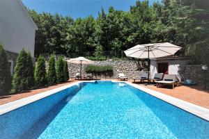 a swimming pool with two umbrellas next to a house at Vila Harmonia in Veprinac