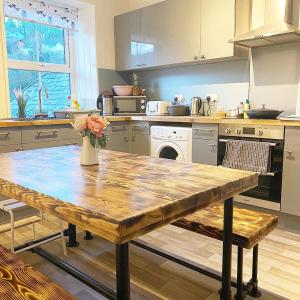 a kitchen with a wooden table with a vase of flowers at Hiraeth Môn in Menai Bridge