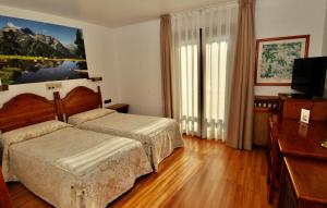 a bedroom with two beds and a flat screen tv at Hotel Petit Lacreu in Salardú