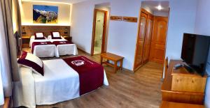 a hotel room with two beds and a flat screen tv at Hotel Petit Lacreu in Salardú