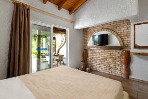 um quarto com uma cama e uma televisão numa parede de tijolos em Elefteria Apts & Suites em Kolimbia