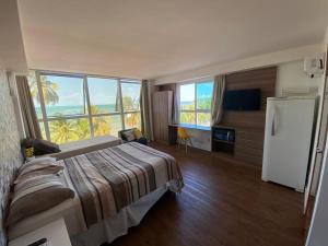 a bedroom with a bed and a refrigerator and windows at Flat vista Mar in João Pessoa
