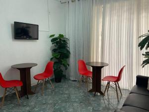 a living room with two tables and red chairs at Belém Hotel in São Paulo