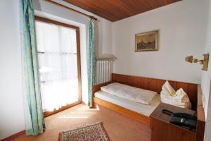 um pequeno quarto com uma cama e uma janela em Hotel Neumayr em Munique