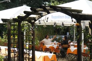 two people sitting at a table under an umbrella at Hotel Neumayr in Munich
