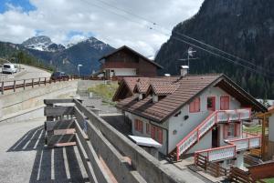 ein Gebäude mit roten Fenstern neben einem Berg in der Unterkunft Appartamento Col Val di Fassa con Terrazza BAGNI RINNOVATI 2023 in Campitello di Fassa