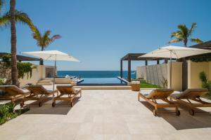 a patio with chairs and umbrellas and the ocean at 1 Homes Preview Cabo in Cabo San Lucas
